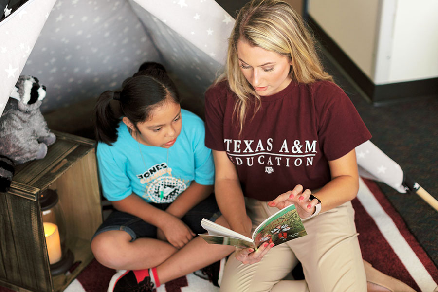 A teacher reads a book to a young girl.